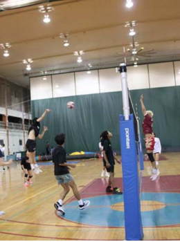 Volleyball players jump to hit the ball during an indoor game.